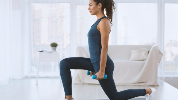 Sporty Hispanic girl doing lunges with dumbbells at home, empty space cardic yoga - healthtimes.me